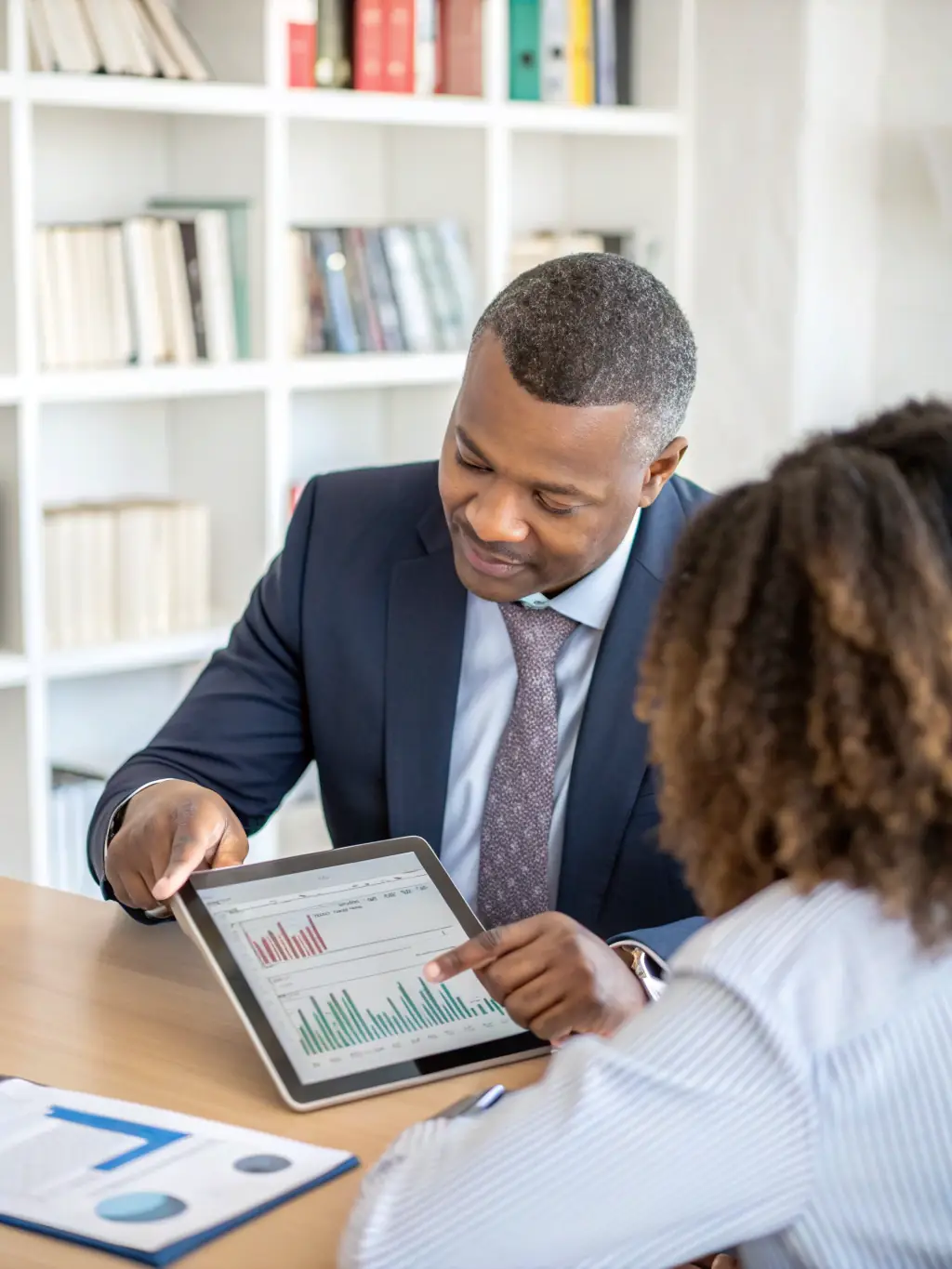 A professional South African financial coach assisting a client with tax documents in a modern office setting, emphasizing personalized service.